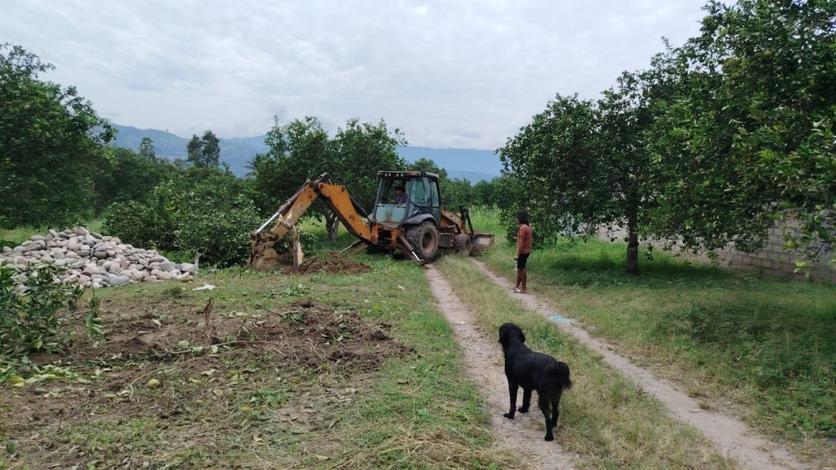 Retroexcavadora trabajando junto a un montón de piedras de río
